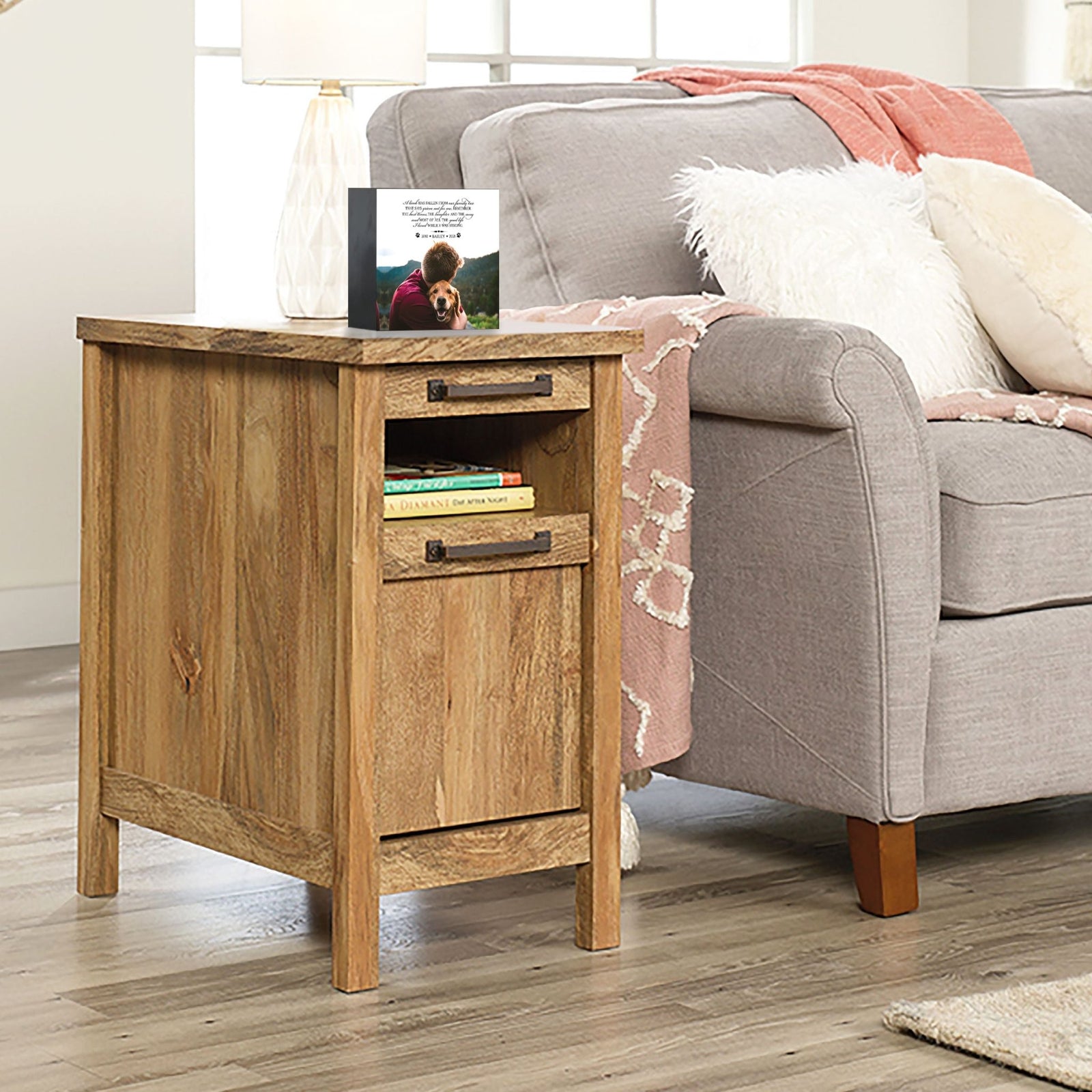 Personalized pet photo urn shadow box, elegantly placed on a side table next to a gray couch in a modern living room. This wooden pet urn for ashes doubles as a sympathy gift for the loss of a pet and a shadow box memorial to honor beloved pets.