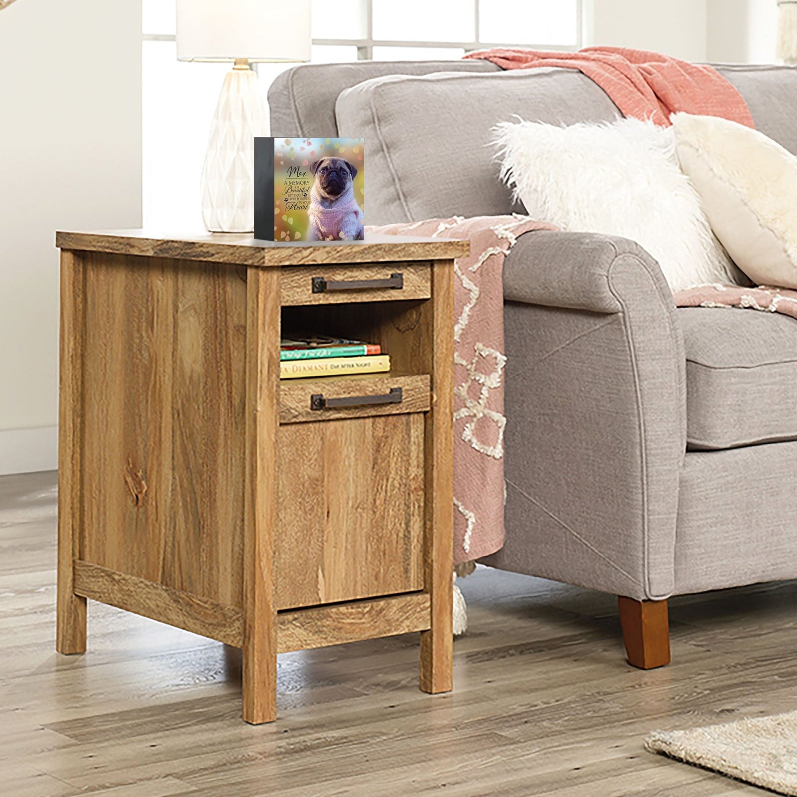 Personalized pet photo urn shadow box, elegantly placed on a side table next to a gray couch in a modern living room. This wooden pet urn for ashes doubles as a sympathy gift for the loss of a pet and a shadow box memorial to honor beloved pets.