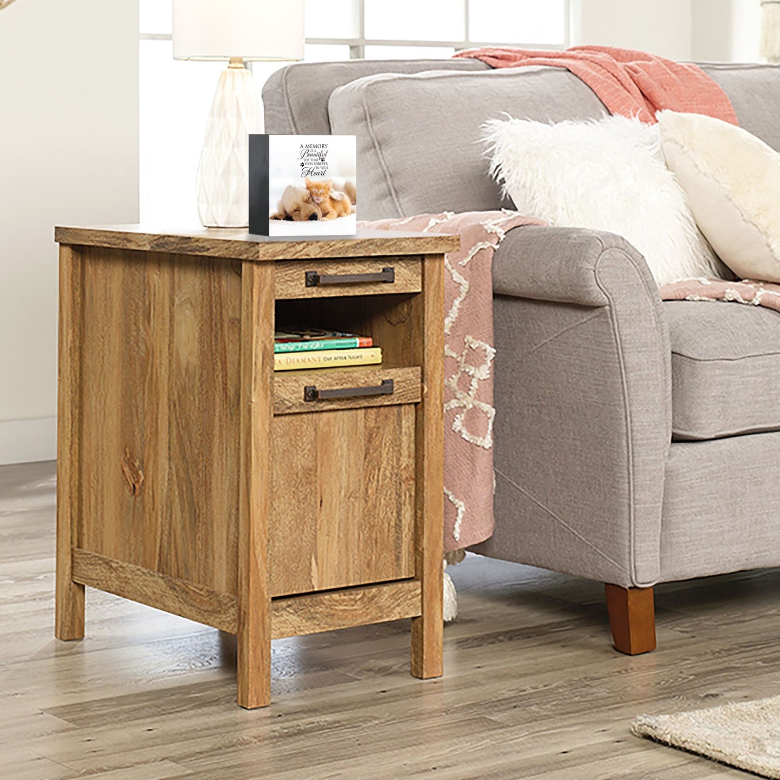 Personalized pet photo urn shadow box, elegantly placed on a side table next to a gray couch in a modern living room. This wooden pet urn for ashes doubles as a sympathy gift for the loss of a pet and a shadow box memorial to honor beloved pets.