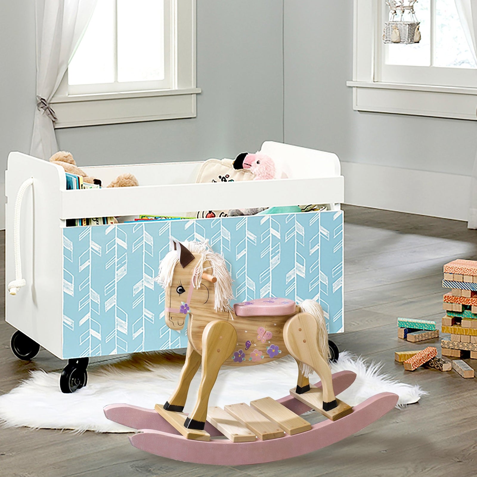 Pink Rocking horse with butterfly beside white crib in nursery