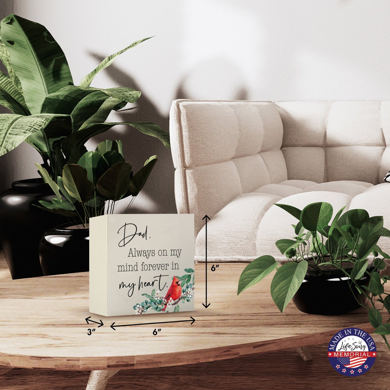 Modern wooden shadow box urn for human ashes, showcased on a minimalist wooden coffee table. This memorial urn, adorned with a cardinal and floral design, blends seamlessly with lush green indoor plants and cozy, contemporary furniture, making it an ideal keepsake for adult ashes.