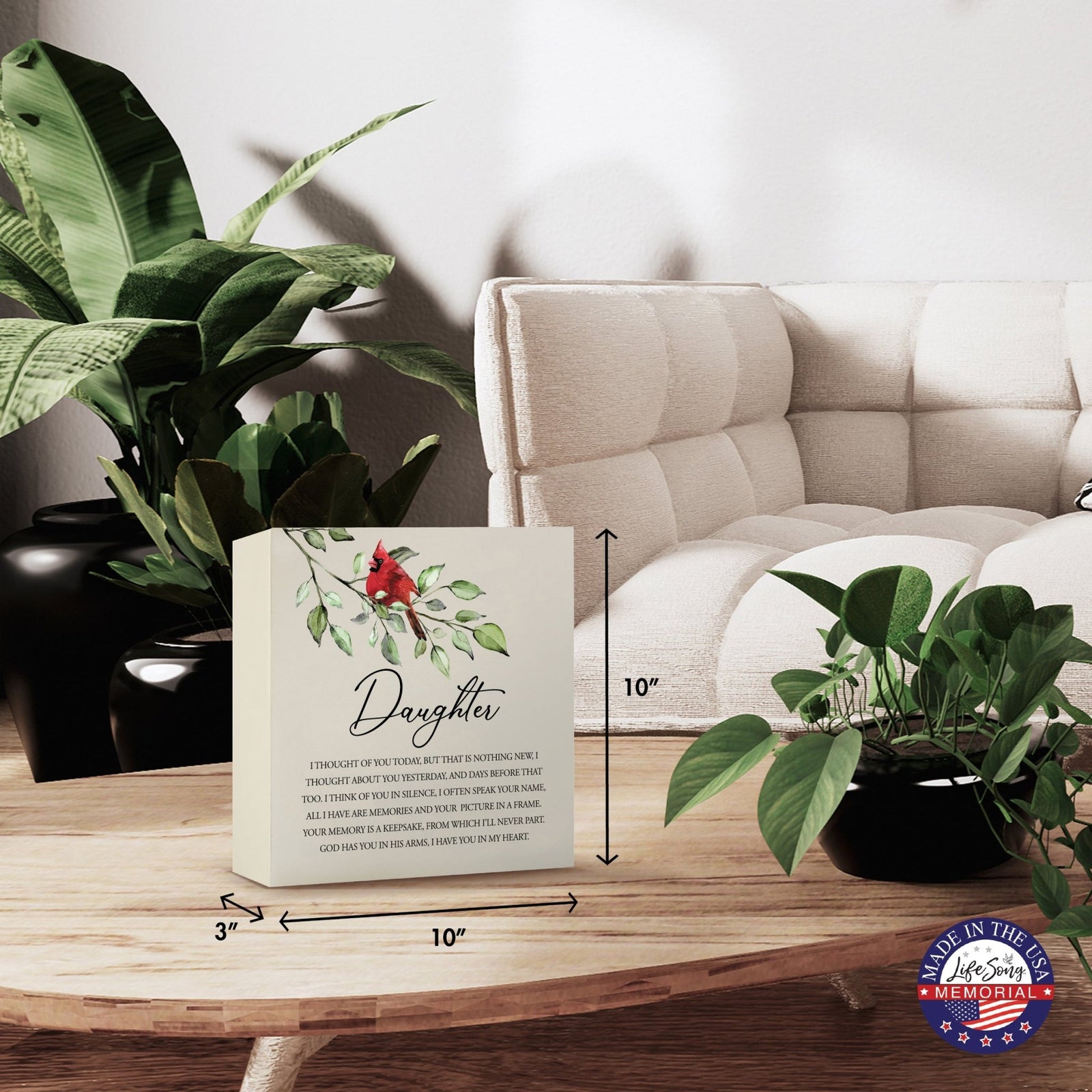 Modern wooden shadow box urn for daughter, showcased on a minimalist wooden coffee table. This memorial urn, adorned with a cardinal and floral design, blends seamlessly with lush green indoor plants and cozy, contemporary furniture, making it an ideal keepsake for adult ashes.