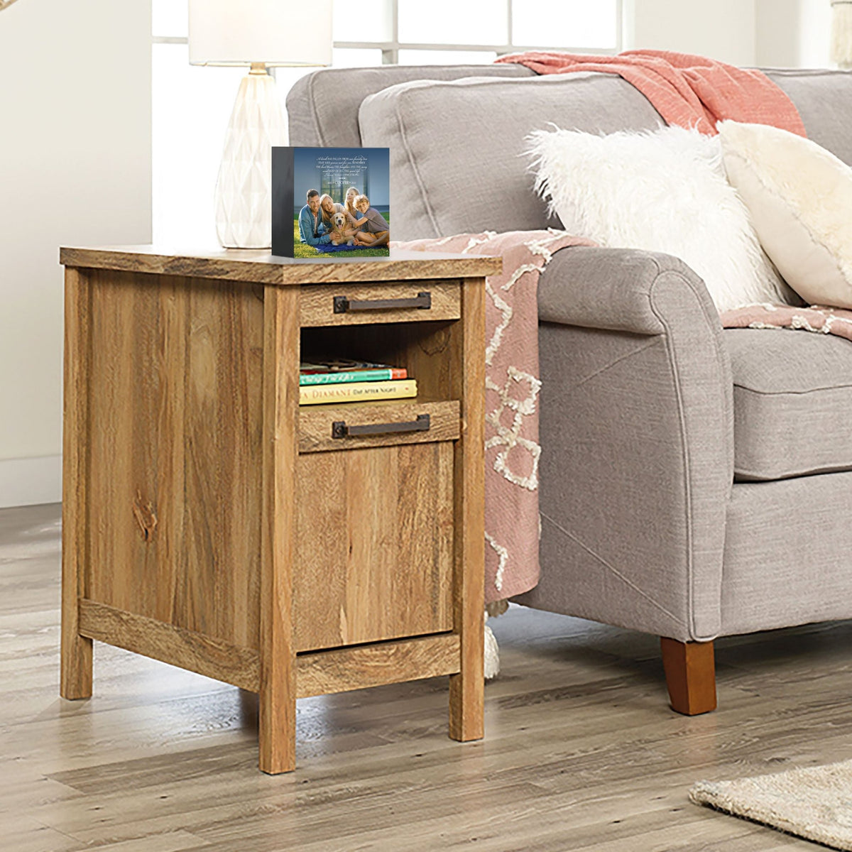 Personalized pet photo urn shadow box, elegantly placed on a side table next to a gray couch in a modern living room. This wooden pet urn for ashes doubles as a sympathy gift for the loss of a pet and a shadow box memorial to honor beloved pets.