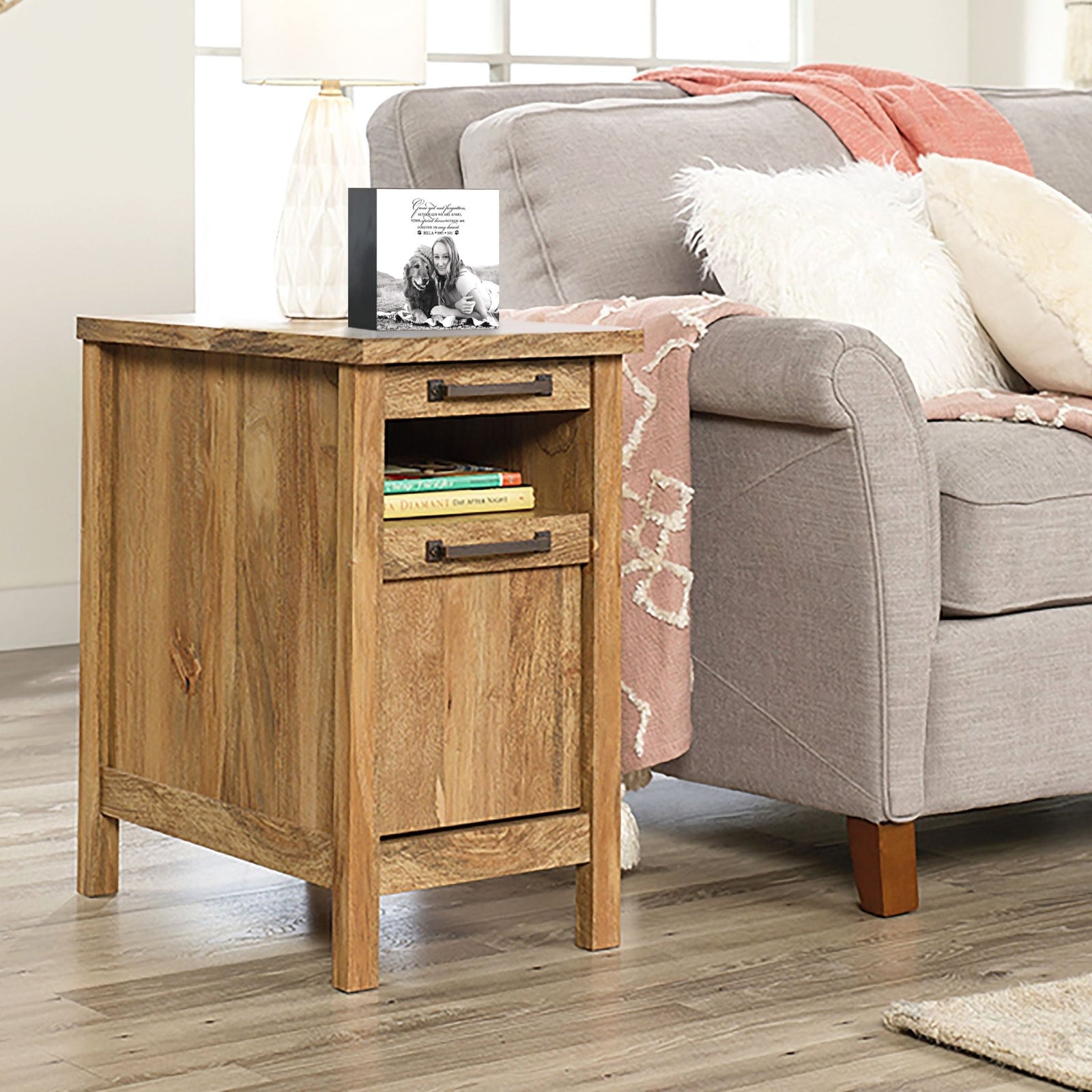 Personalized pet photo urn shadow box, elegantly placed on a side table next to a gray couch in a modern living room. This wooden pet urn for ashes doubles as a sympathy gift for the loss of a pet and a shadow box memorial to honor beloved pets.