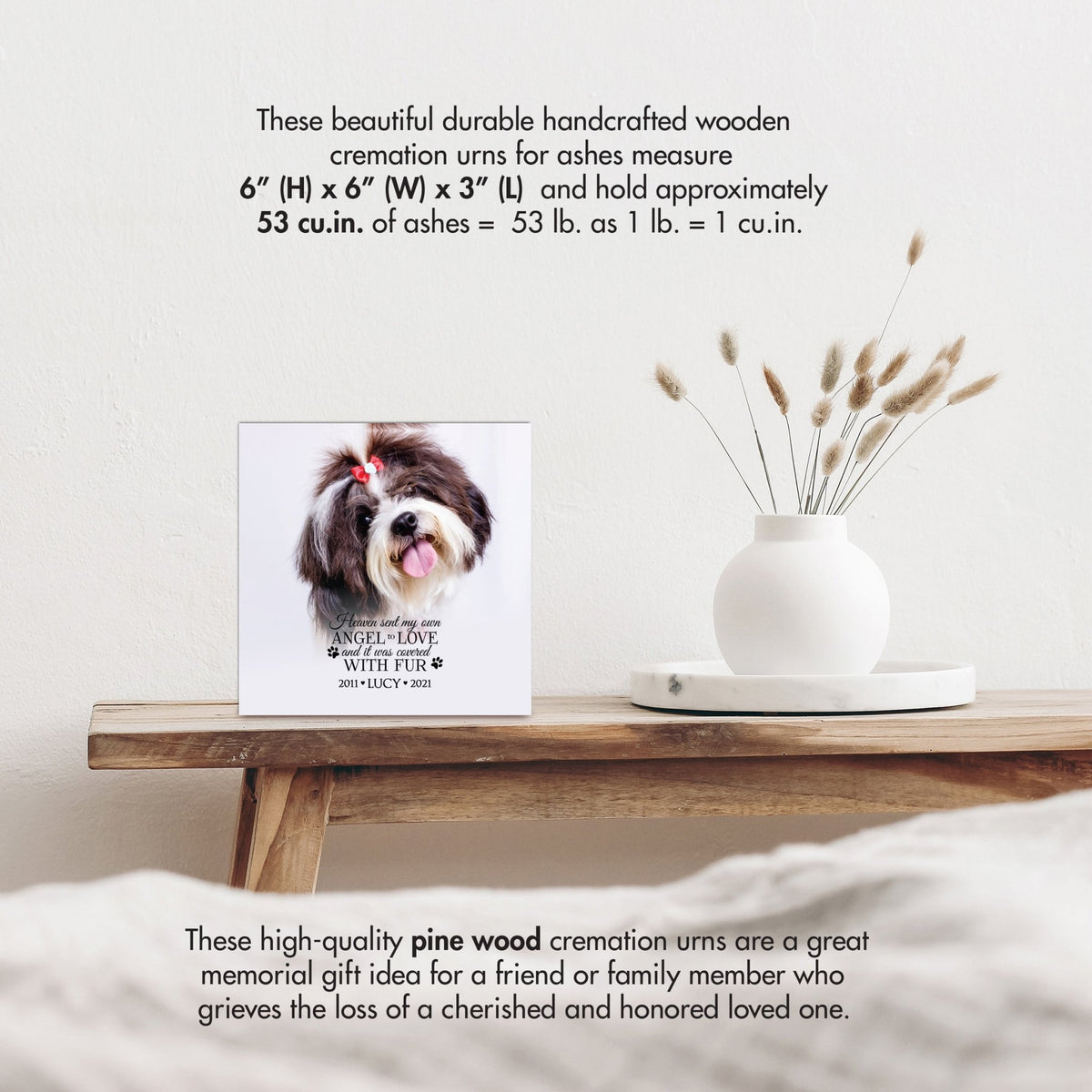 A wooden pet urn with size details, highlighting its handcrafted design with a white vase of pampas grass.