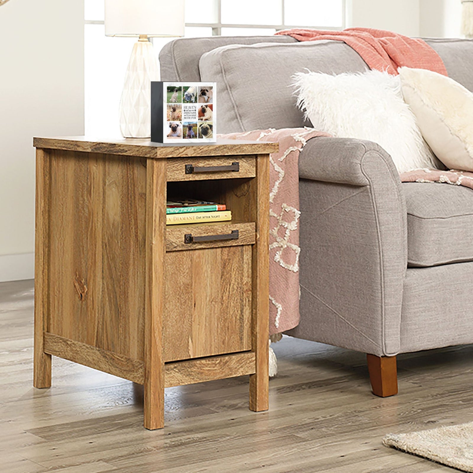 A personalized pet urn placed on a wooden side table beside a cozy gray couch.