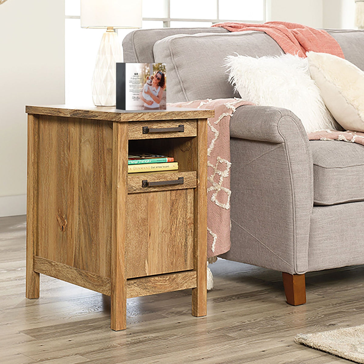 A personalized pet urn placed on a wooden side table beside a cozy couch.