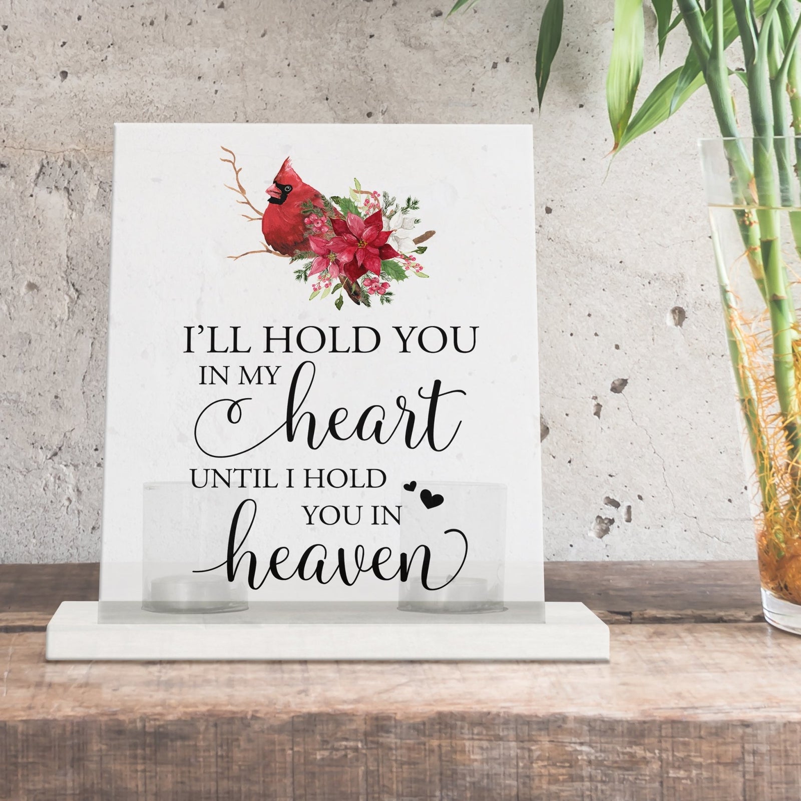 A solemn memorial display featuring a Lifesong Milestones Cardinal Memorial Frosted Acrylic Sign with Base and Votive Candle Holder. The tealight candle holder provides a warm glow, while votive candles surround it, creating a touching memory.