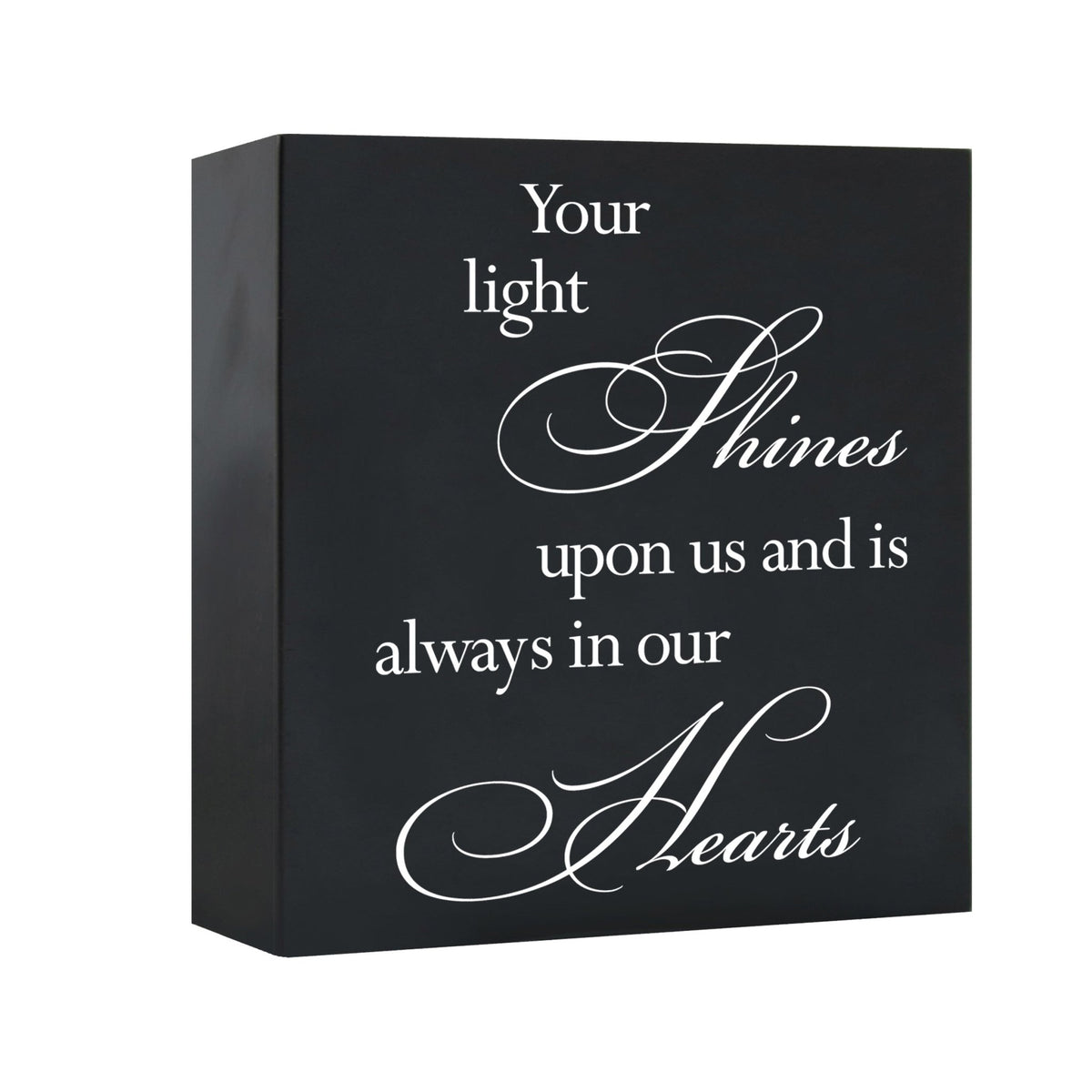 A close-up view of the LifeSong Milestones Memorial Shadow Box Urn for human ashes showcases its sleek black design and meaningful engraving, "Your light shines upon us and is always in our hearts." This urn embodies a heartfelt way to honor and cherish the memory of a loved one.