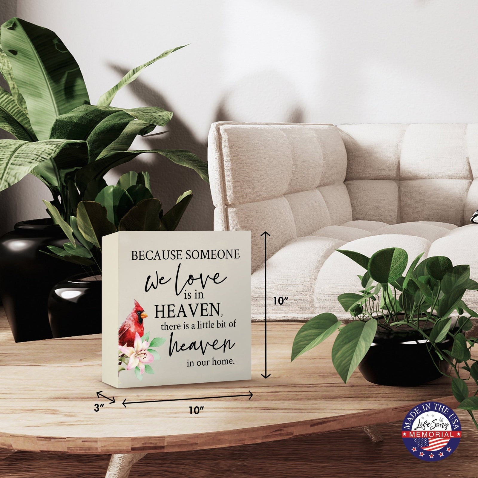 Modern wooden shadow box urn for human ashes, showcased on a minimalist wooden coffee table. This memorial urn, adorned with a cardinal and floral design, blends seamlessly with lush green indoor plants and cozy, contemporary furniture, making it an ideal keepsake for adult ashes.
