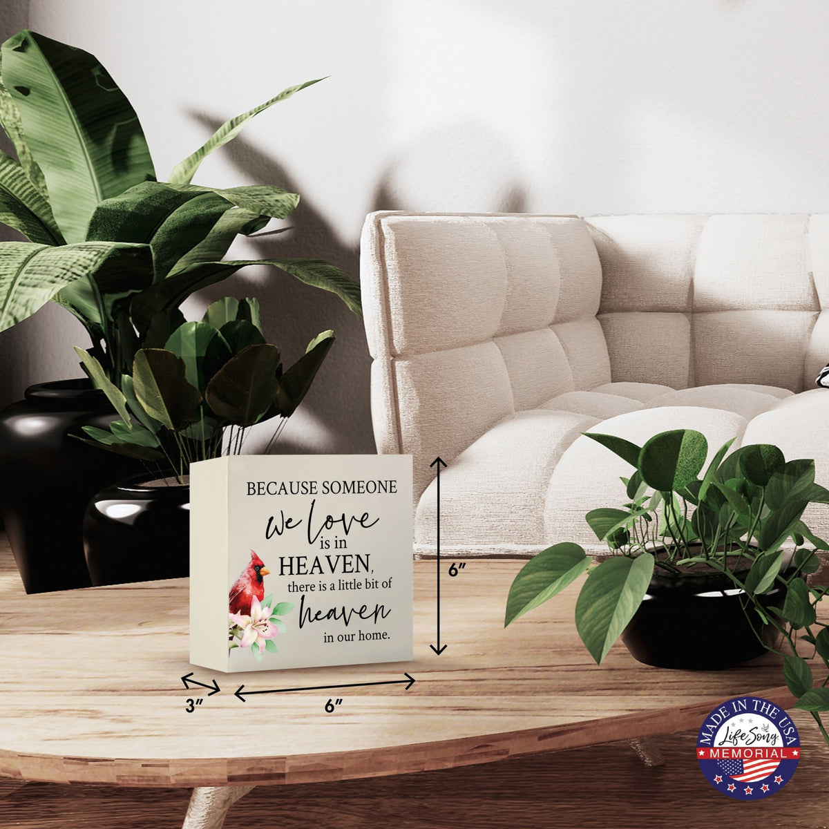 Modern wooden shadow box urn for human ashes, showcased on a minimalist wooden coffee table. This memorial urn, adorned with a cardinal and floral design, blends seamlessly with lush green indoor plants and cozy, contemporary furniture, making it an ideal keepsake for adult ashes.