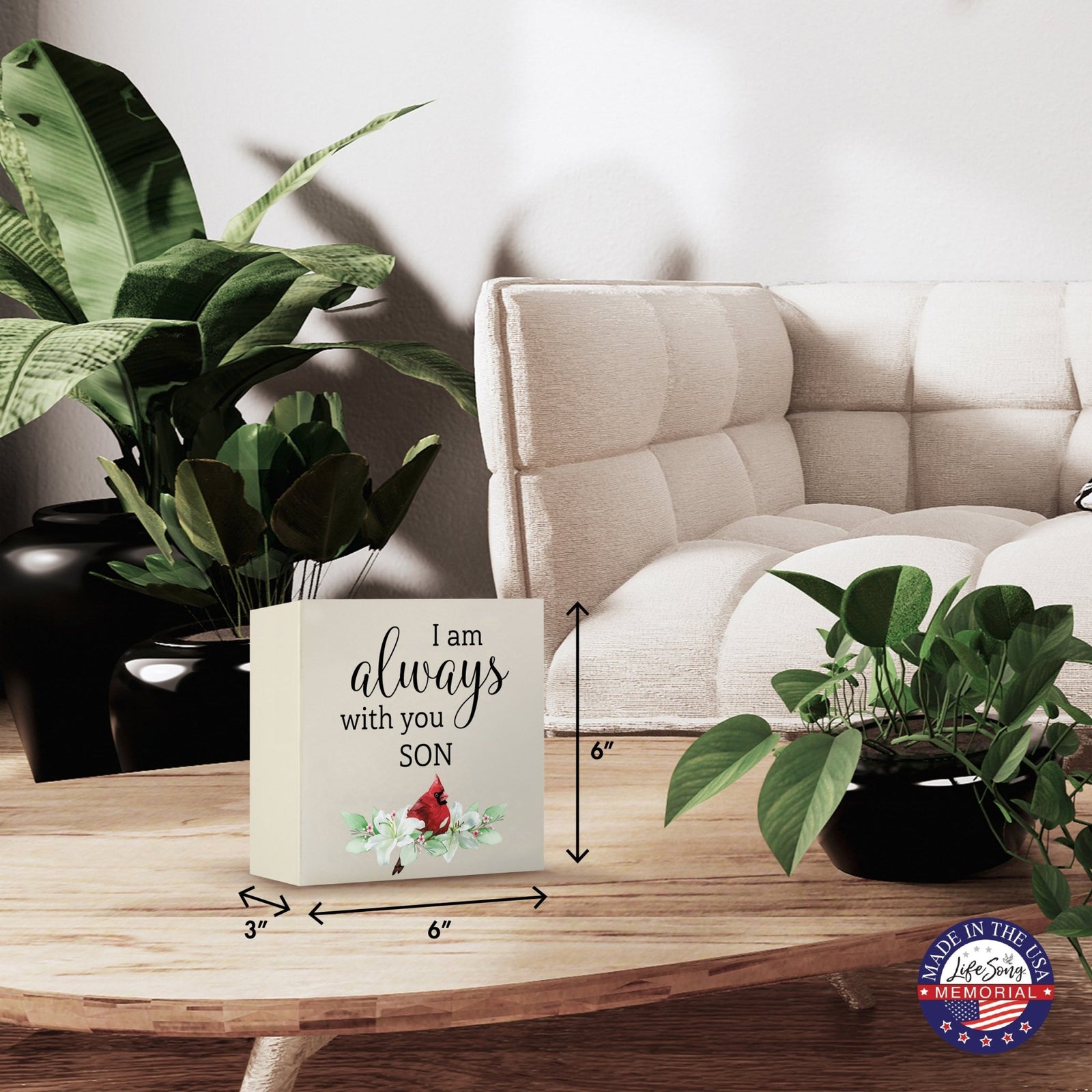 Modern wooden shadow box urn for human ashes, showcased on a minimalist wooden coffee table. This memorial urn, adorned with a cardinal and floral design, blends seamlessly with lush green indoor plants and cozy, contemporary furniture, making it an ideal keepsake for adult ashes.