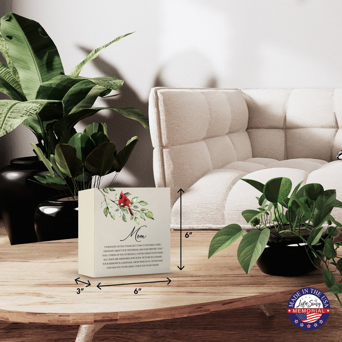 Modern wooden shadow box urn for human ashes, showcased on a minimalist wooden coffee table. This memorial urn, adorned with a cardinal and floral design, blends seamlessly with lush green indoor plants and cozy, contemporary furniture, making it an ideal keepsake for adult ashes.
