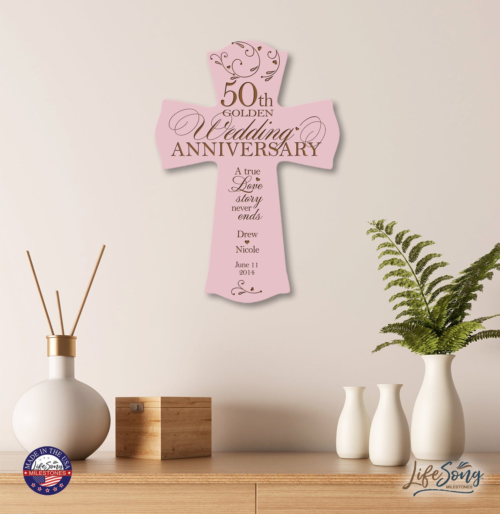 Soft pink 50th Golden Wedding Anniversary custom cross plaque displayed on wooden shelf with minimalist home décor—personalized Christian wall art with names and date.